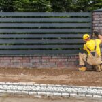 A worker is installing a modern fence.