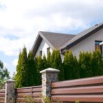 A modern backyard fence at a private cottage home with a green hedge in an upscale residential complex.