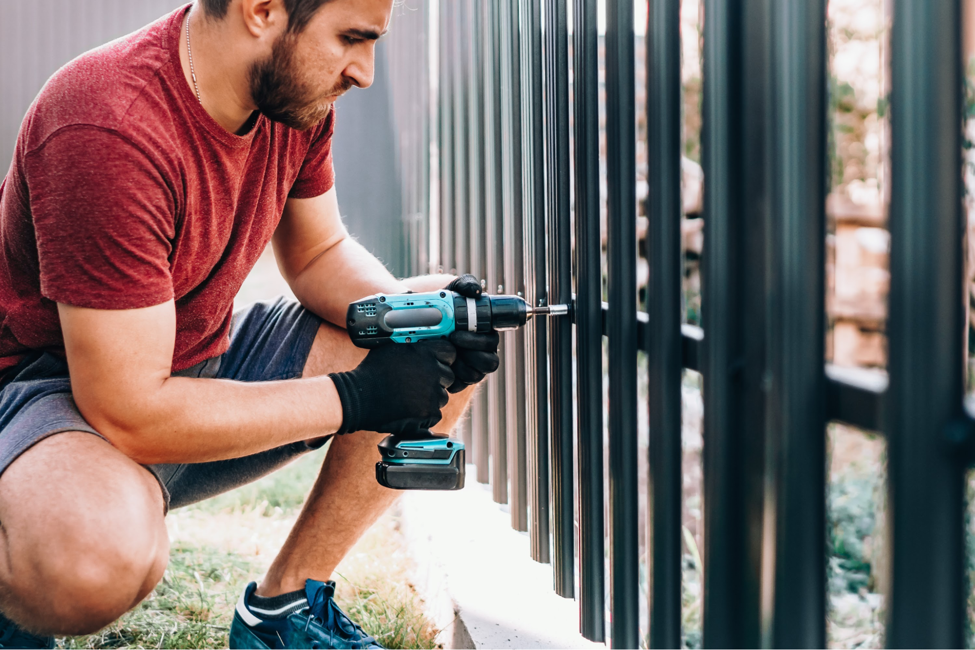 A man using a power tool to install a fence. 