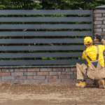 A contractor installing a metal fence.