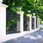 A scenic park alley with a decorative retro-style metal fence enclosure.