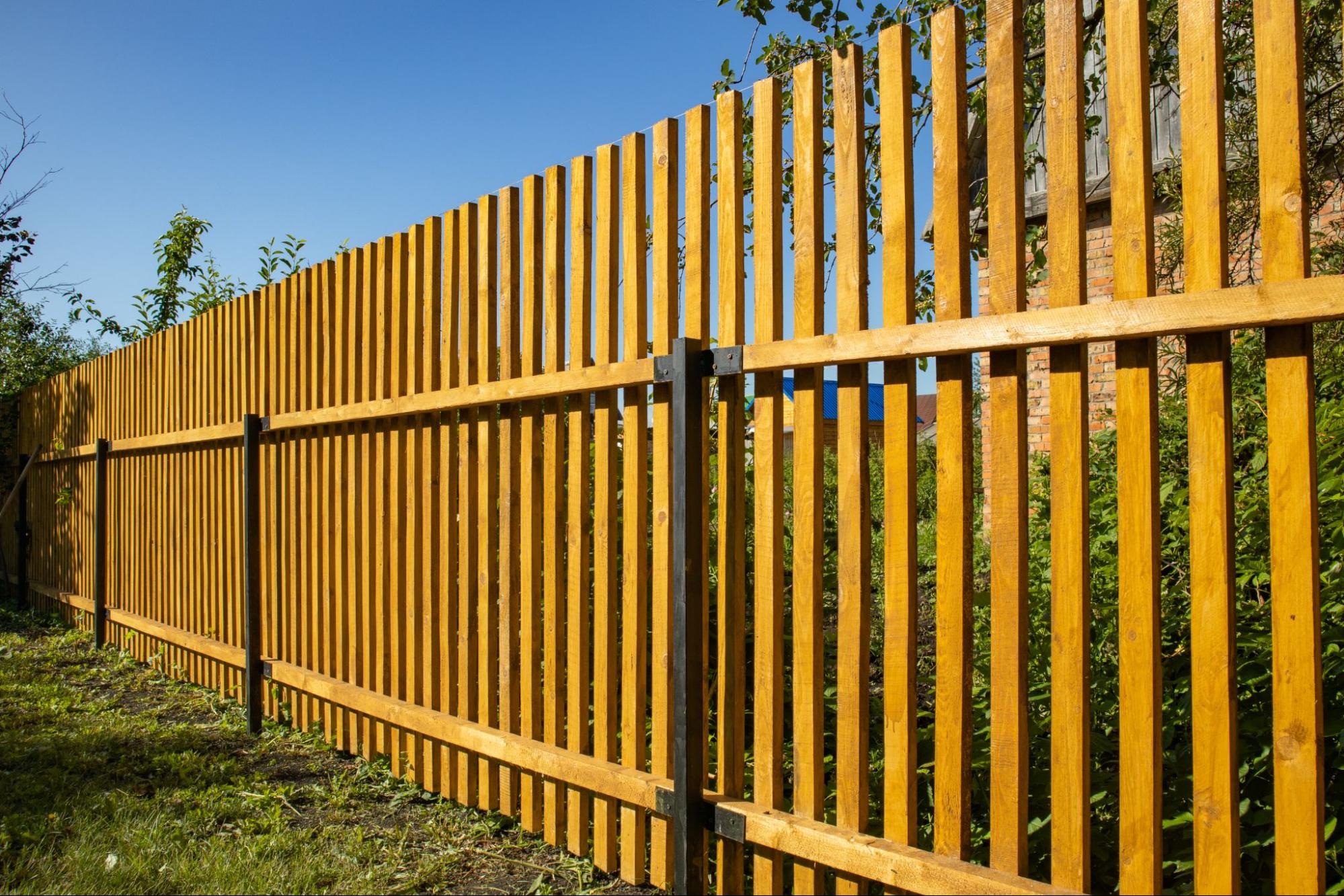 Close-up of new composite picket fence in the backyard of a country house.