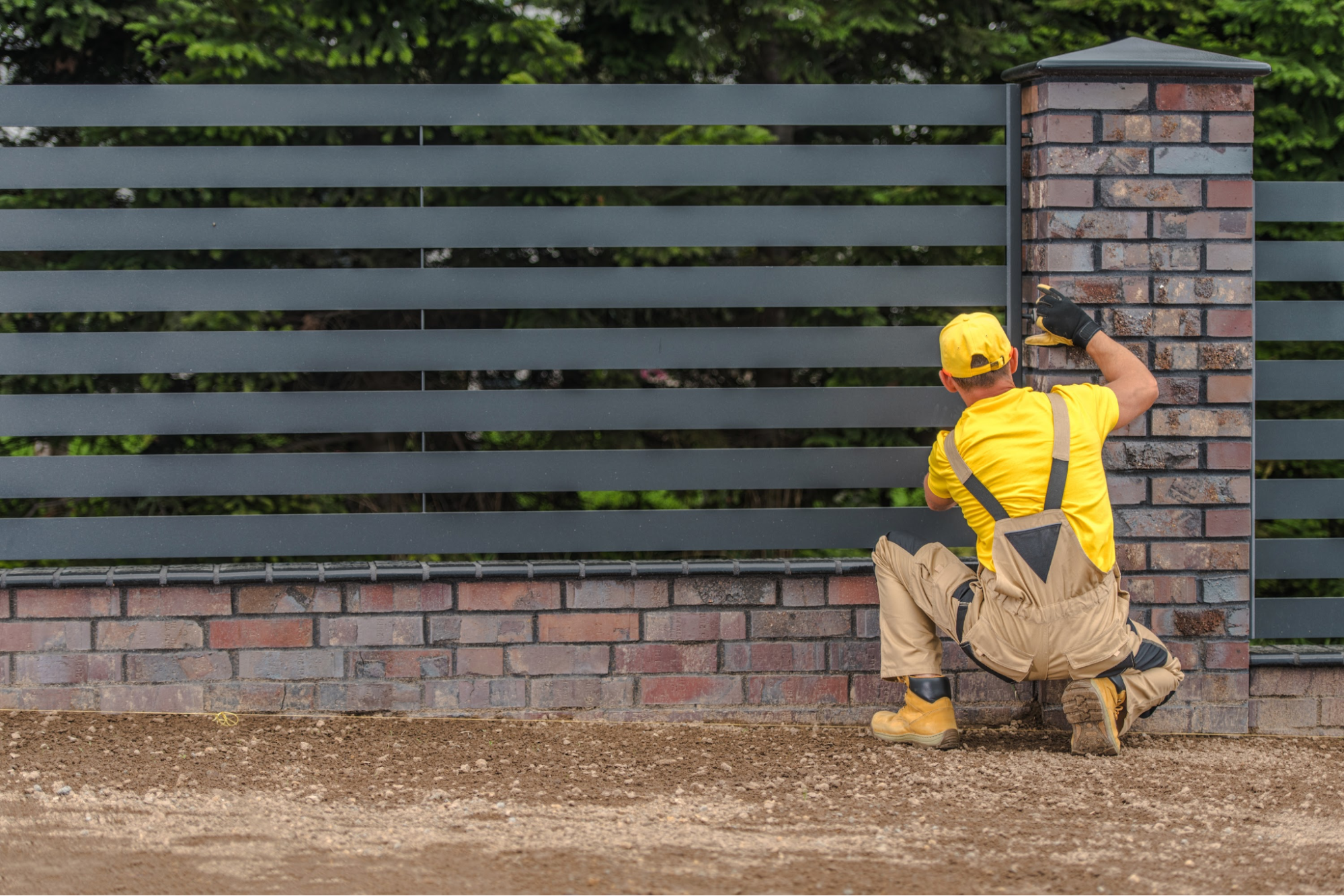 A contractor installing a metal fence.