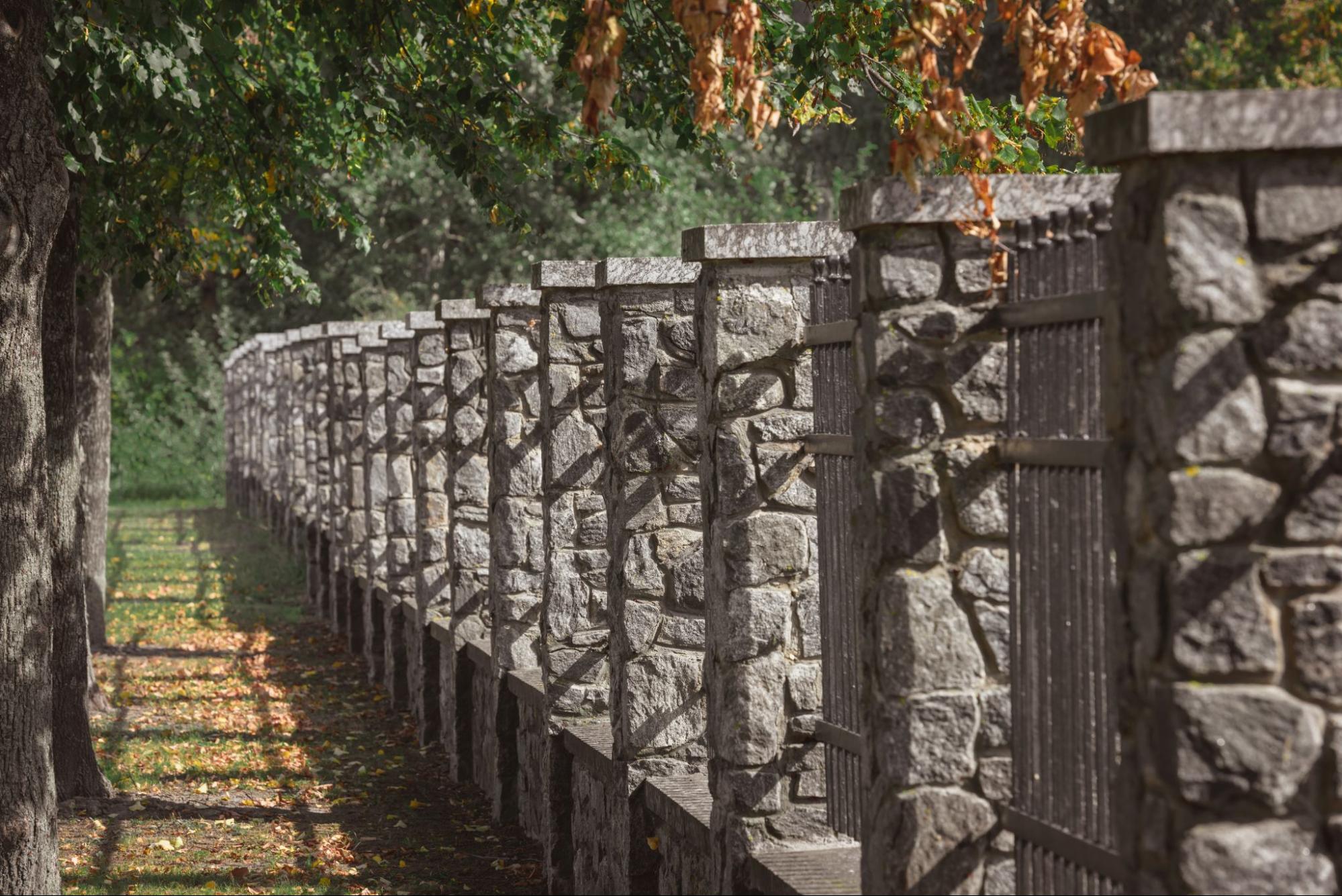 Selective focus on stone fencing beneath shaded outdoor trees.
